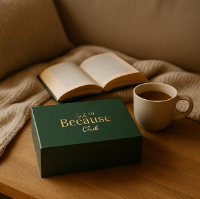 Green box with 'Just Because' text, open book, and coffee cup on a wooden surface.
